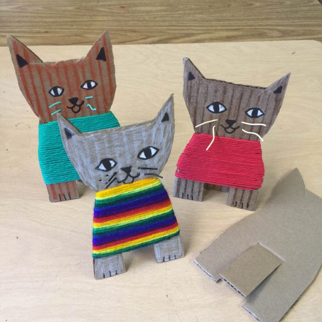 A cardboard craft for kids, wrapping yarn to make a sweater for a kitten.