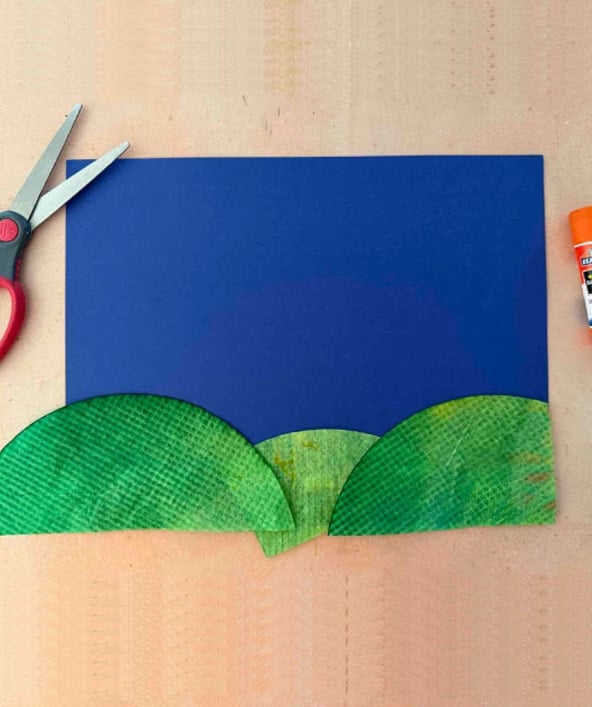 Cutting and arranging painted coffee filters into hills for a fall tree art project.